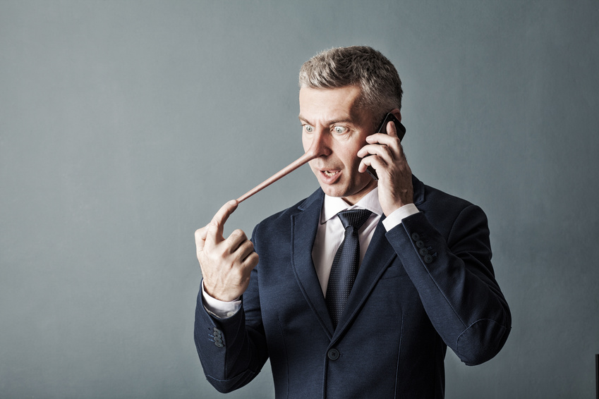 Businessman with long nose on gray wall background. Liar concept.